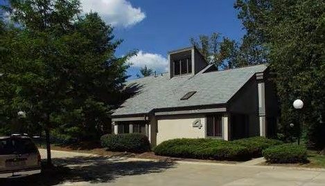 The building at 1617 Akron Peninsula Road in Akron, Ohio: a low building with a gray roof among trees